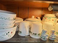 Stacked Winterberry bowls, mugs, lidded bowls, teapot, snowman shakers on shelf