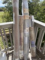 Four rolled Safavieh rugs in plastic wrap leaning against railing