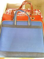 Front view of blue document case in front, red tote and floral cosmetic bag behind