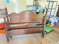 Headboard, footboard and bottom rail leaning against wall, brown finish