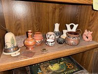 Shelf view showing entire grouping of Southwestern miniature ceramics, stone plaque, bell ornament and lizard figurine