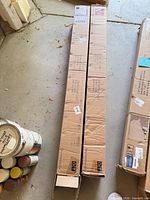 Two long cardboard boxes containing umbrellas on garage floor