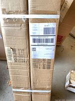 Two long cardboard cartons containing artificial trees