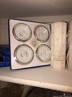 Boxed Italian crystal & silver-rim coaster set alongside ivory pillar candle
