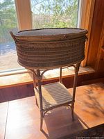 Full view of wicker sewing basket side table showing form and lower shelf