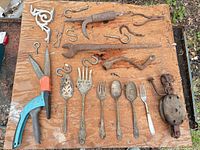 Assorted tools, hooks, utensils, pulley and shears on board