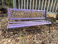 Full view of garden bench showing purple slats, cast iron frame, and wear