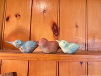 All three carved wooden birds side by side on shelf