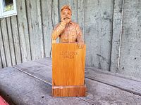 Front view of signed wood auctioneer carving showing podium with Livestock Sales engraving