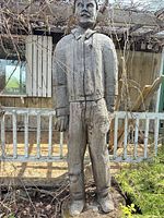Full view of standing wooden lumberjack statue on rock base