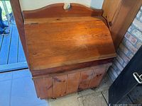 Top view of wooden firewood storage box showing slanted lid and backplate