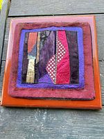Front view of quilted textile wall hanging showing entire patchwork and orange border
