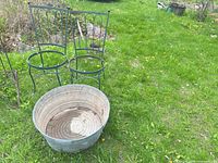 Two green metal chair frames and a galvanized wash tub on grass