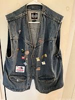 Front of blue denim vest Risen with patches and pins visible