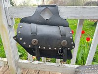 Front view of one black leather studded motorcycle saddlebag hung on railing