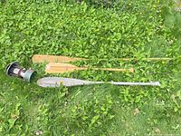 Overview showing Coleman lantern and three wooden paddles on grass