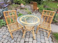 Round glass top rattan table with two rattan side chairs on patio