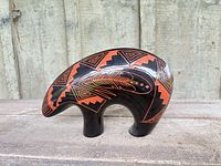 Profile view of black and red sgraffito pottery bear