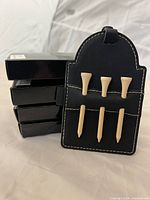 Four boxed tags with one tag displayed front showing three wooden tees