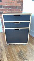 Front view of cabinet showing three drawers and casters