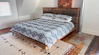 Full view of assembled king bed with bedding showing reclaimed wood frame, headboard, hairpin legs