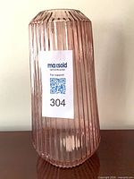 Full view of pink ribbed glass vase with MaxSold sticker