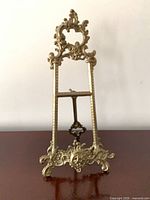 Front view of ornate brass easel showing decorative scrollwork