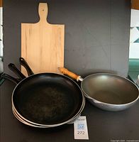Group shot of three pans, wok and cutting board