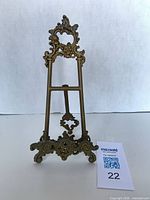 Front view of ornate brass easel stand with MaxSold tag