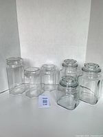 All six glass canisters grouped, showing two shapes and lids