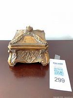 front view of ornate gold ceramic trinket box with lid and feet