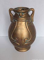 Front view showing bronze finish, green patina accents, scroll relief and twin handles