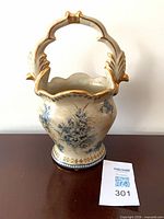 Front view showing blue floral pattern, gold gilt rim and handle