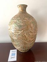 Front view of carved ceramic vase showing relief pattern and patina