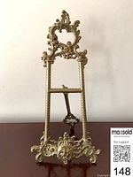 Front view of ornate brass easel showing detailed scrollwork and feet