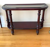 Full view of dark cherry console table with glass inset top and lower shelf