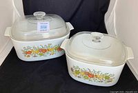 Two CorningWare casseroles with lids, vegetable pattern visible