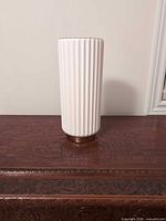 Full front view of fluted white ceramic vase on table
