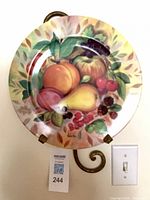 Front view of porcelain plate on hanger, fruit still life design visible