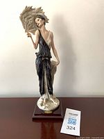 Full front view of porcelain figurine on wood base with tag visible