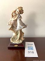 Front view of Giuseppe Armani porcelain figurine on wood base with Maxsold lot card