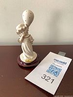 Front view of porcelain girl with balloon on wood base showing gold Florence plaque