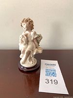 Front view of Giuseppe Armani porcelain girl with rabbit figurine on wood base