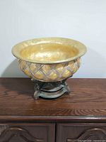 Front view of ornate gold-tone resin bowl on tripod base