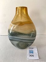 Front view of swirled amber and green art glass vase with MaxSold lot card