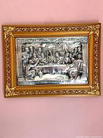 Front view of framed silver-tone relief plaque