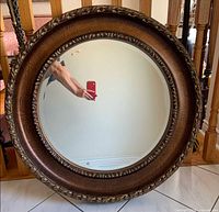 Front view of round bronze-finish mirror showing ornate frame and reflective surface