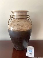 Front view of two-tone ceramic vase with ring handles, wear visible