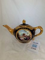 Front view showing teapot shape, gold spout, handle and lid, transfer scene