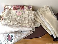 stack of folded tablecloths showing lace, floral, damask fabrics
